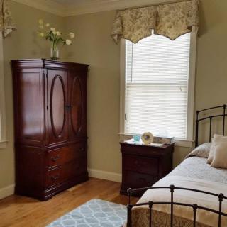 A traditional bedroom with a wooden wardrobe and metal bed frame.