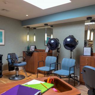 A cozy hair salon interior featuring styling chairs, hair dryers, and mirrors.