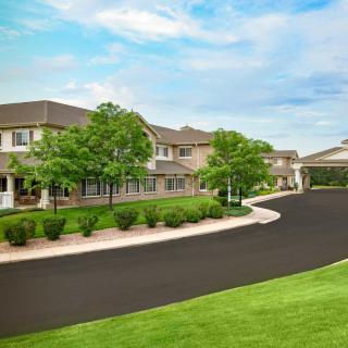 A scenic view of a residential building with a lush green landscape and clear blue sky.