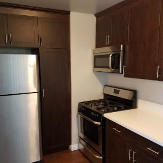 A modern kitchen featuring stainless steel appliances and dark wooden cabinets.