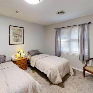 A cozy bedroom featuring two twin beds with a window and nightstand between them.