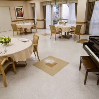 An elegant dining room with round tables and a piano.
