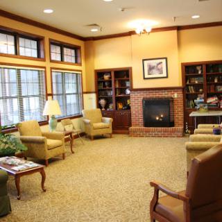 A cozy living room with comfortable seating, a warm fireplace, and shelves filled with books.