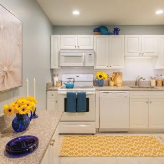 A bright and modern kitchen featuring white cabinetry, blue accents, and cheerful yellow decor.
