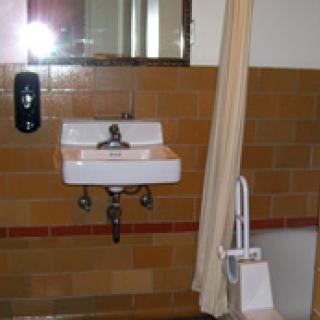 A bathroom with a wall-mounted sink, mirror, and shower curtain.