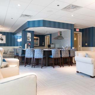 A modern living space featuring a spacious seating area, blue walls, and a kitchen with bar stools.