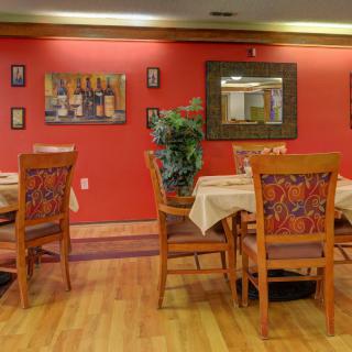 A cozy restaurant dining area with wooden tables and chairs, adorned with wall art.
