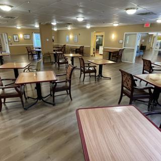 An empty dining area with wooden tables and chairs, illuminated by ceiling lights.