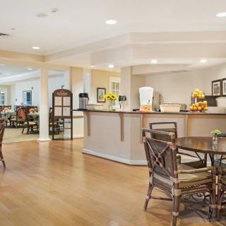 A spacious cafe with wooden floors and bright lighting, featuring several tables and chairs.