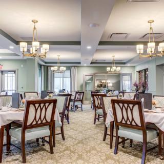 An elegant dining room with neatly arranged tables and chandeliers.