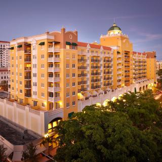 A brightly lit hotel building in an urban setting during the evening.