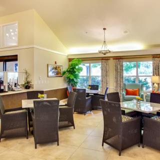 A modern dining area with wicker chairs, large windows, and indoor plants providing a cozy atmosphere.