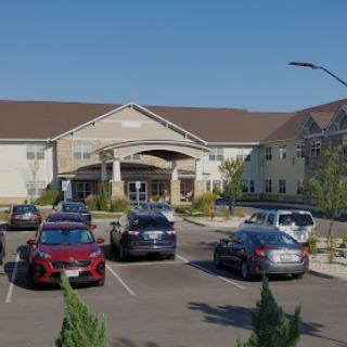 A view of a commercial building with a parking lot filled with cars on a sunny day.