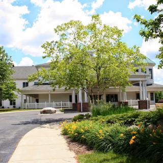 A serene view of a building surrounded by lush greenery and a bright sky.