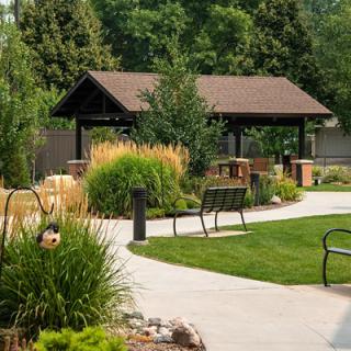 A peaceful park setting with a pavilion, benches, and landscaped pathways.