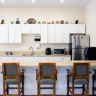 A modern kitchen with a countertop, bar stools, and various appliances.