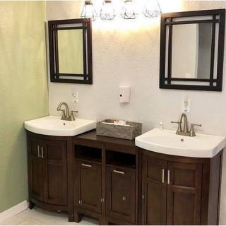 A modern bathroom with double sinks, stylish mirrors, and a central lighting fixture.
