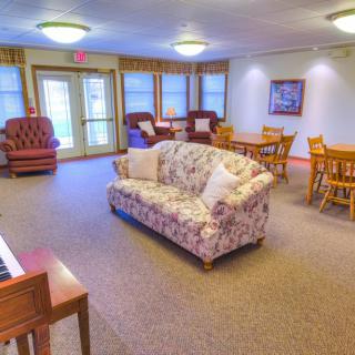 A cozy lounge area with a floral sofa, chairs, and tables.