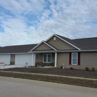 A suburban house with a driveway and front yard under a cloudy sky.