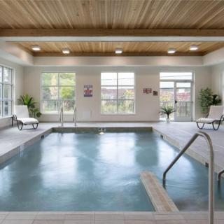 A modern indoor swimming pool with ample natural light and comfortable lounge chairs.