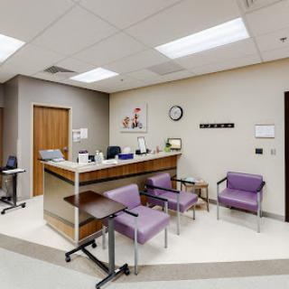 A modern waiting room in a medical office, featuring a reception desk and comfortable seating.