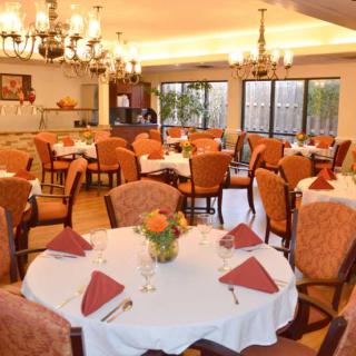 An elegant dining area with neatly arranged tables and chairs, adorned with chandeliers.