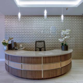 A modern reception area featuring an elegantly designed wooden front desk and stylish decor.