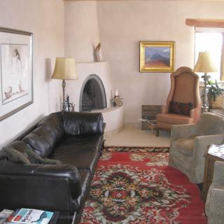 A cozy living room featuring a leather sofa, armchairs, a patterned rug, and a built-in fireplace with decorative elements.