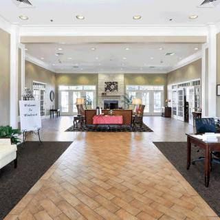 A modern lobby with a central reception desk, bright lighting, and elegant furnishing.