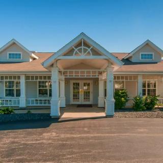 A front view of a residential building with a spacious porch and driveway.