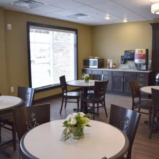 A cozy indoor dining area with round tables, chairs, and decorative flowers.