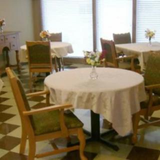 A cozy dining area with tables covered in white tablecloths and floral centerpieces.