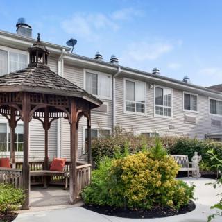 A peaceful residential backyard featuring a wooden gazebo and lush landscaping.