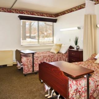 A hospital room with two beds and a large window.
