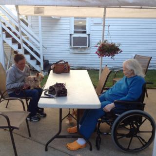 Two people sitting at a table outdoors, one in a wheelchair.