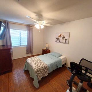 A cozy bedroom with a single bed, dresser, and exercise equipment.