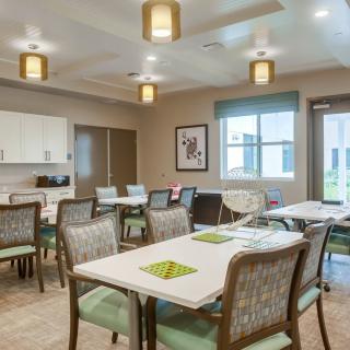 A modern dining room interior with tables and chairs arranged neatly under warm lighting.