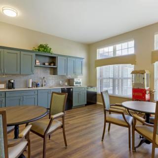 A cozy kitchen and dining area with tables, chairs, and large windows.
