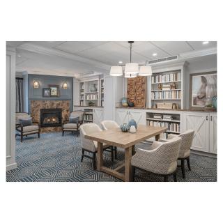 A modern living and dining area featuring a cozy fireplace, elegant furniture, and neatly organized bookshelves.