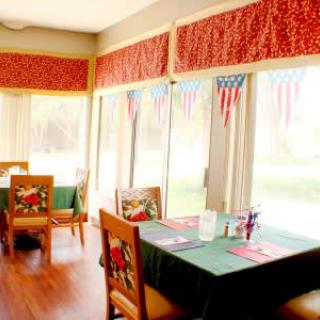 A cozy restaurant dining area with decorated tables and large windows letting in natural light.