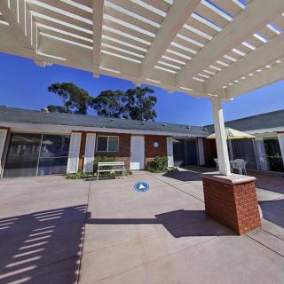 A sunny courtyard with a pergola and brick pillar providing shade.