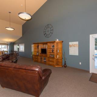 A cozy living room with leather sofas, a large wooden entertainment cabinet, and a prominent wall clock.