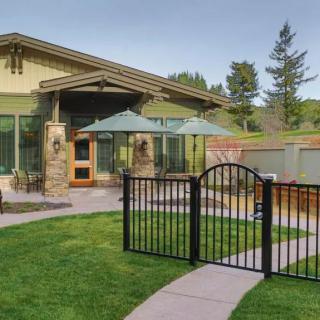 A modern house with a well-maintained lawn, patio area, and a black metal gate.
