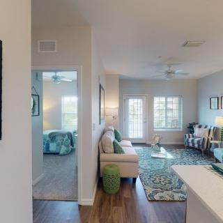 A modern apartment interior featuring a cozy living room with stylish furniture and decor, leading into a bedroom.