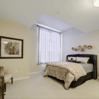 A neatly arranged bedroom with a large window and decorative art.