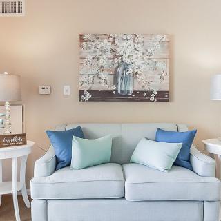 A cozy living room with a pastel sofa, decorative pillows, and artwork on the wall.