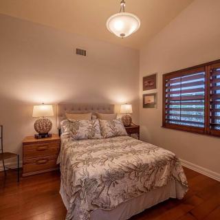 A cozy bedroom with a bed, nightstands, lamps, and window shutters.