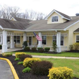 A charming yellow house with a well-maintained garden and an American flag displayed at the entrance.