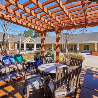 A cozy outdoor patio area with a wooden pergola and comfortable seating arrangements.