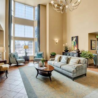 A spacious and well-lit living room with modern decor, featuring large windows, comfortable sofas, and elegant furnishings.